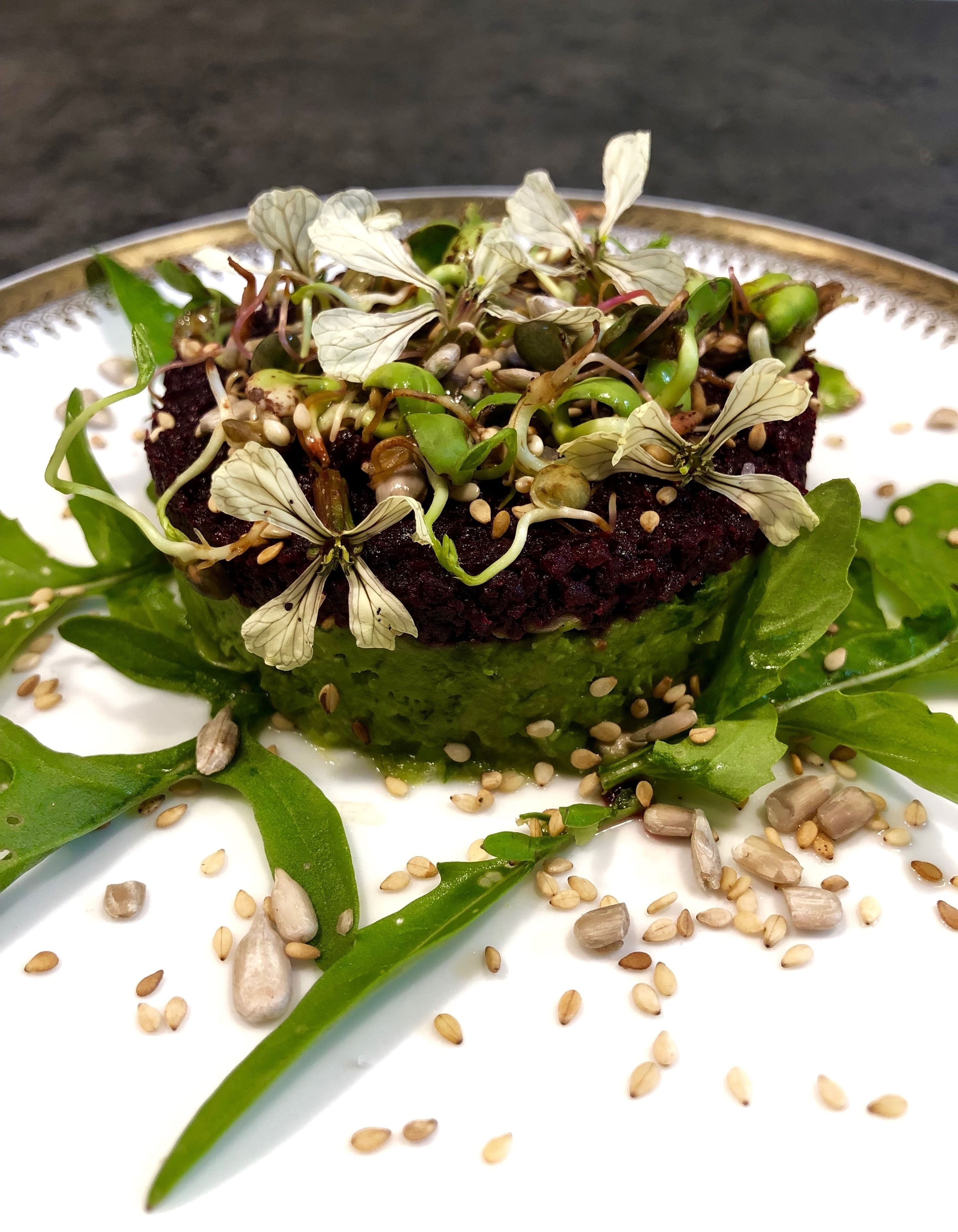 A dish with a dark base, green leaves, and white flowers on a white plate.