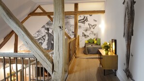 A loft bedroom with exposed wooden beams, a fireplace, a sofa, and a small table with a plant. - Domaine de l'Ocrerie (Pourrain)