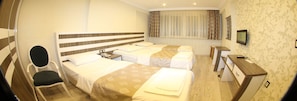 A hotel room with two beds, a desk, a chair, a TV, and a window with curtains.