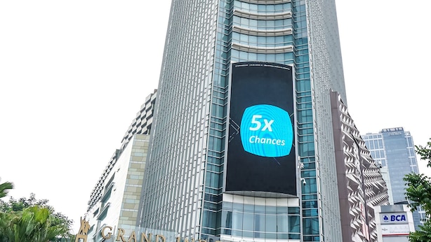 Een hoge, moderne wolkenkrabber met een opvallend bord waarop '5x Chances' staat.