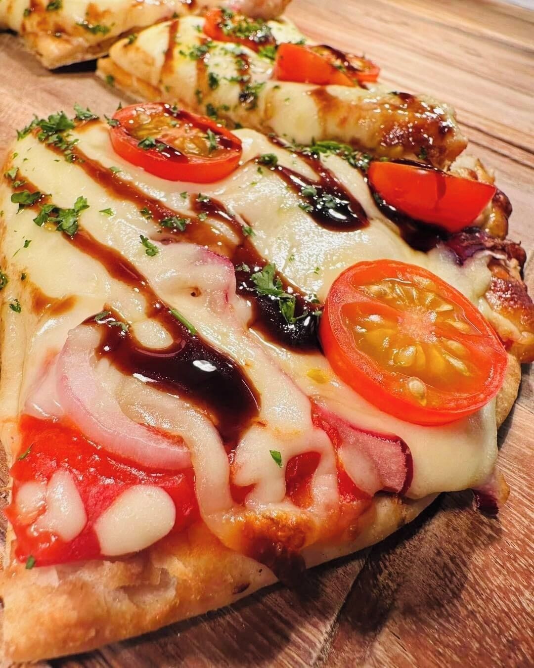 Una pizza con ingredientes y salsa sobre una superficie de madera.
