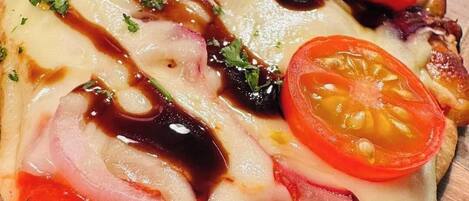 Una pizza con ingredientes y salsa sobre una superficie de madera.