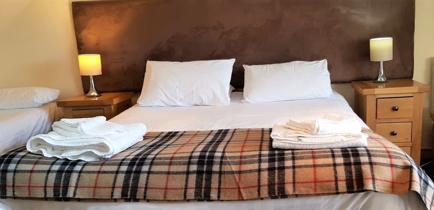 A hotel room with a large bed, two bedside tables, and a headboard.