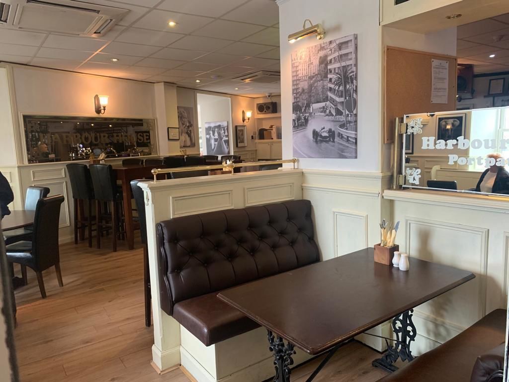 Un restaurante con área de bar, una zona de mesas con cabinas y una pared decorada con una fotografía antigua.