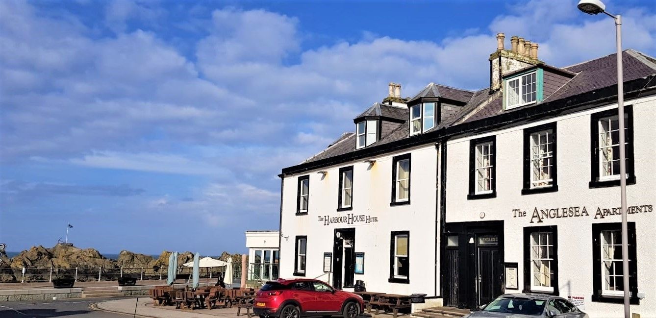 The Anglesea Apartments, a white building with black trim, featuring a prominent entrance and multiple windows.