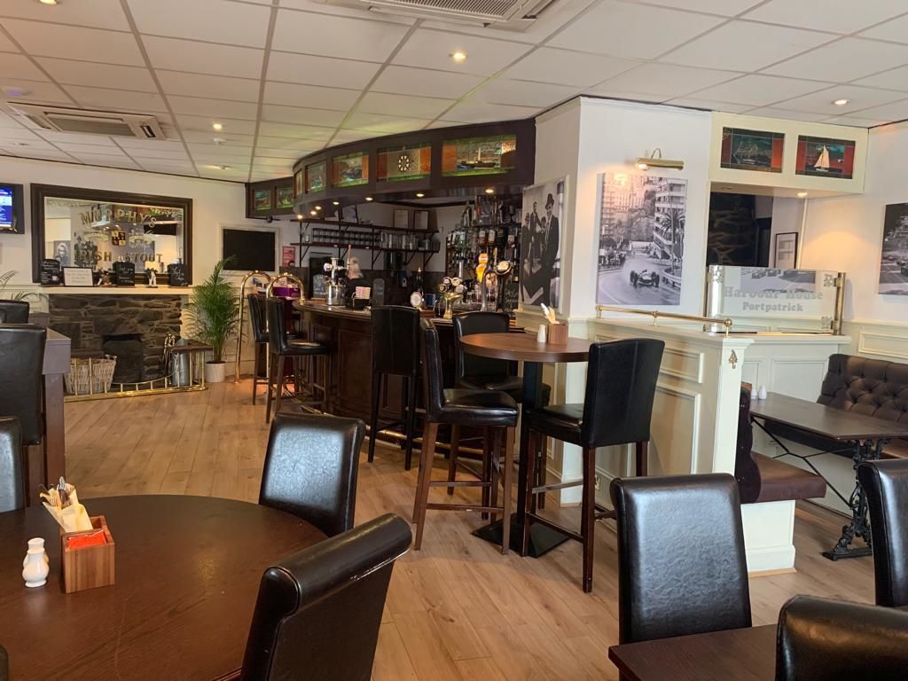 Un restaurante con zona de bar, distintas opciones de asientos, incluyendo mesas redondas y cabinas, y un menú a la vista.