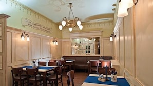 A restaurant interior with wooden tables and chairs, a chandelier, and a wall with a quote.