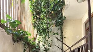 A small outdoor seating area with a table and chairs, surrounded by a concrete wall and a metal fence. - Deeps Hostel (Eskisehir)