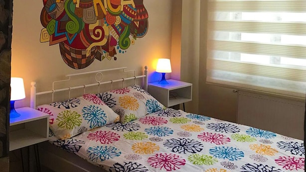 A bedroom with a bed, two bedside tables with lamps, a wall mural with 'AFRICA' written on it, and a window with blinds. - Deeps Hostel (Eskisehir)