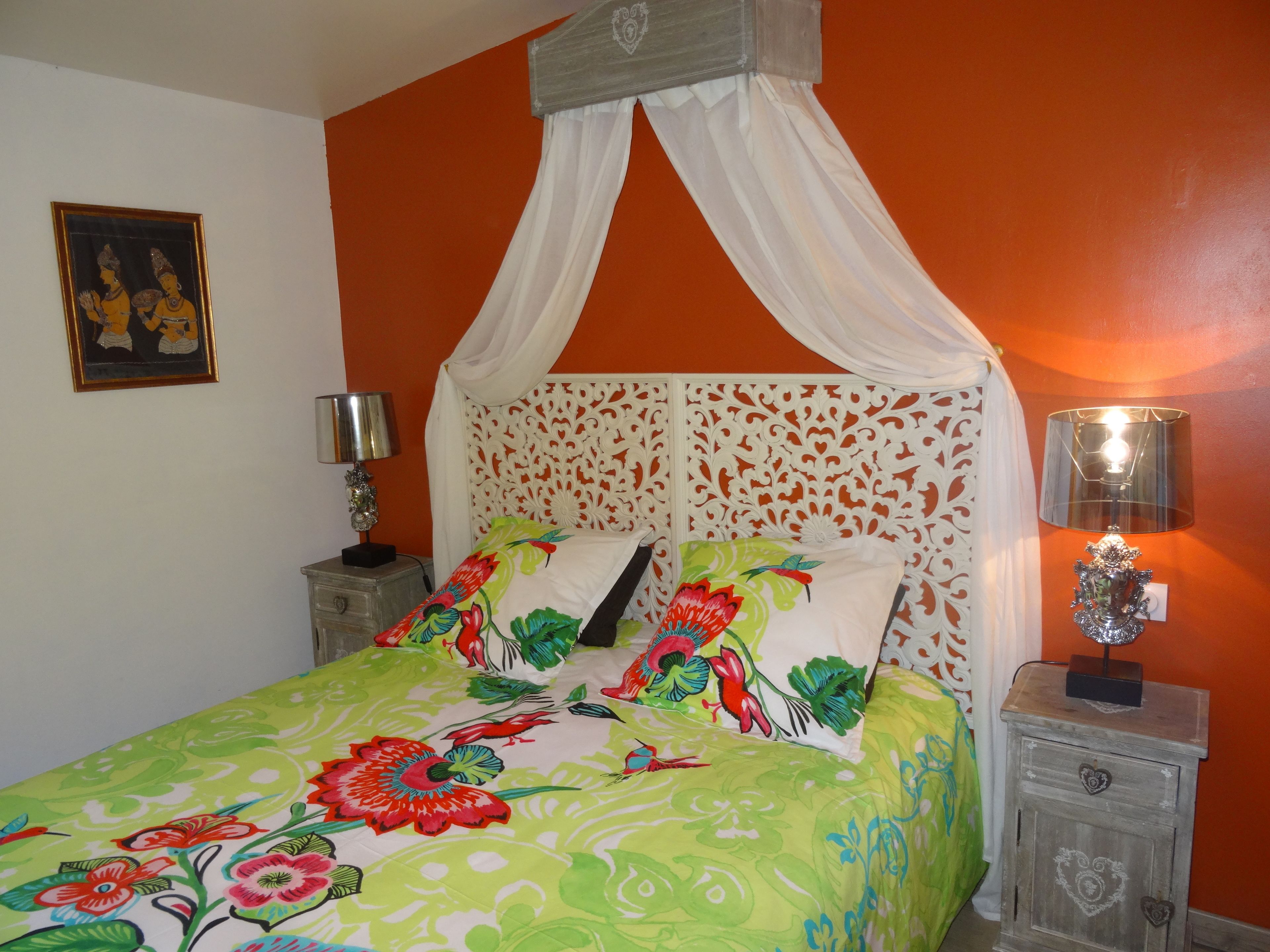 A bed with a floral bedspread, a canopy, and a nightstand with a lamp.