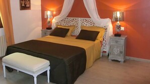 A bedroom with a bed, bedside tables, a bench, and a canopy.