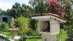A garden with a stone fountain, a Buddha statue, and potted plants.