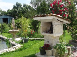 Um jardim com uma fonte de pedra, uma estátua de Buda e plantas em vasos.