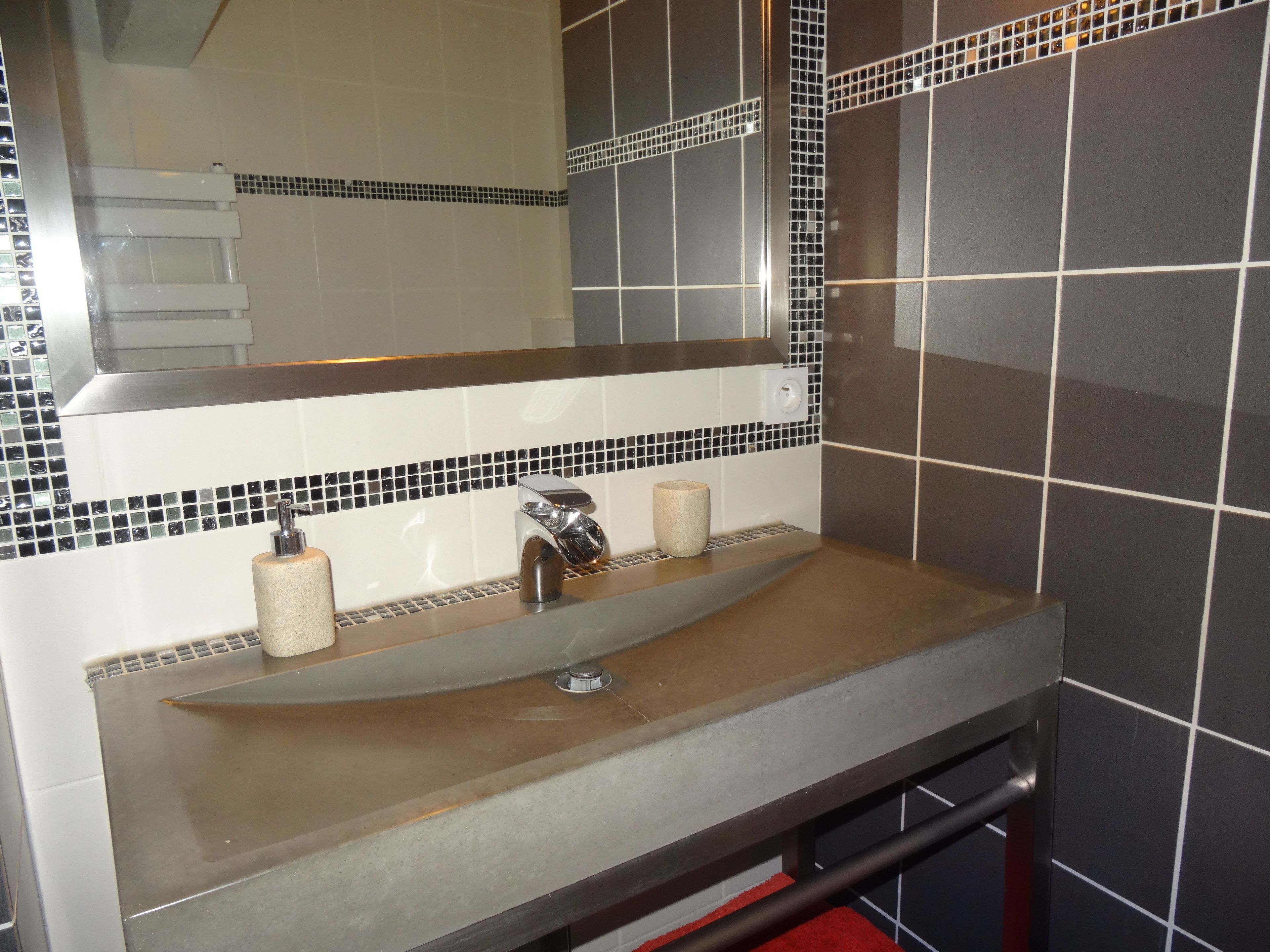 A bathroom with a sink, mirror, and tiled walls.
