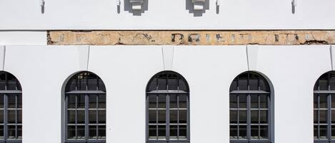 Fachada de edificio con ventanas de arco y un letrero encima.