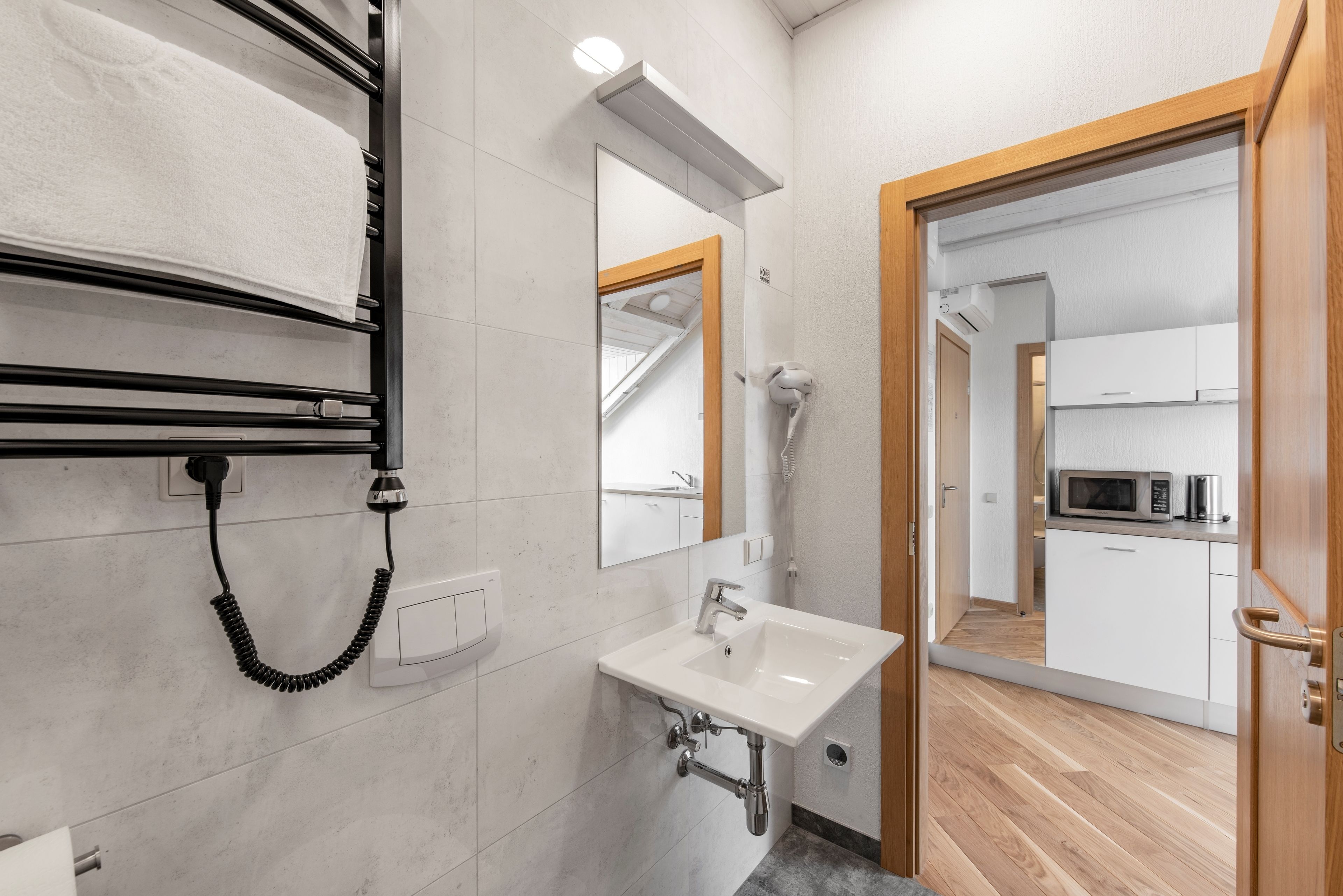 A modern bathroom with a sink, mirror, towel rack, and hairdryer.