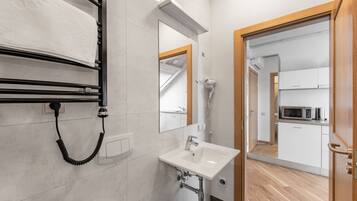 A modern bathroom with a sink, mirror, towel rack, and hairdryer.