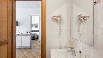 Una habitación de hotel con baño, una cama, un lavabo y un espejo.