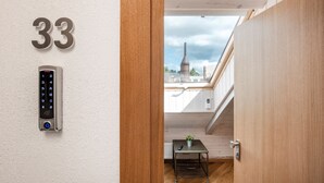 A modern apartment with a digital keypad lock, a view of a cityscape, and a wooden interior.