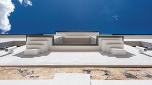 A modern outdoor seating area with geometric white structures and a clear blue sky.