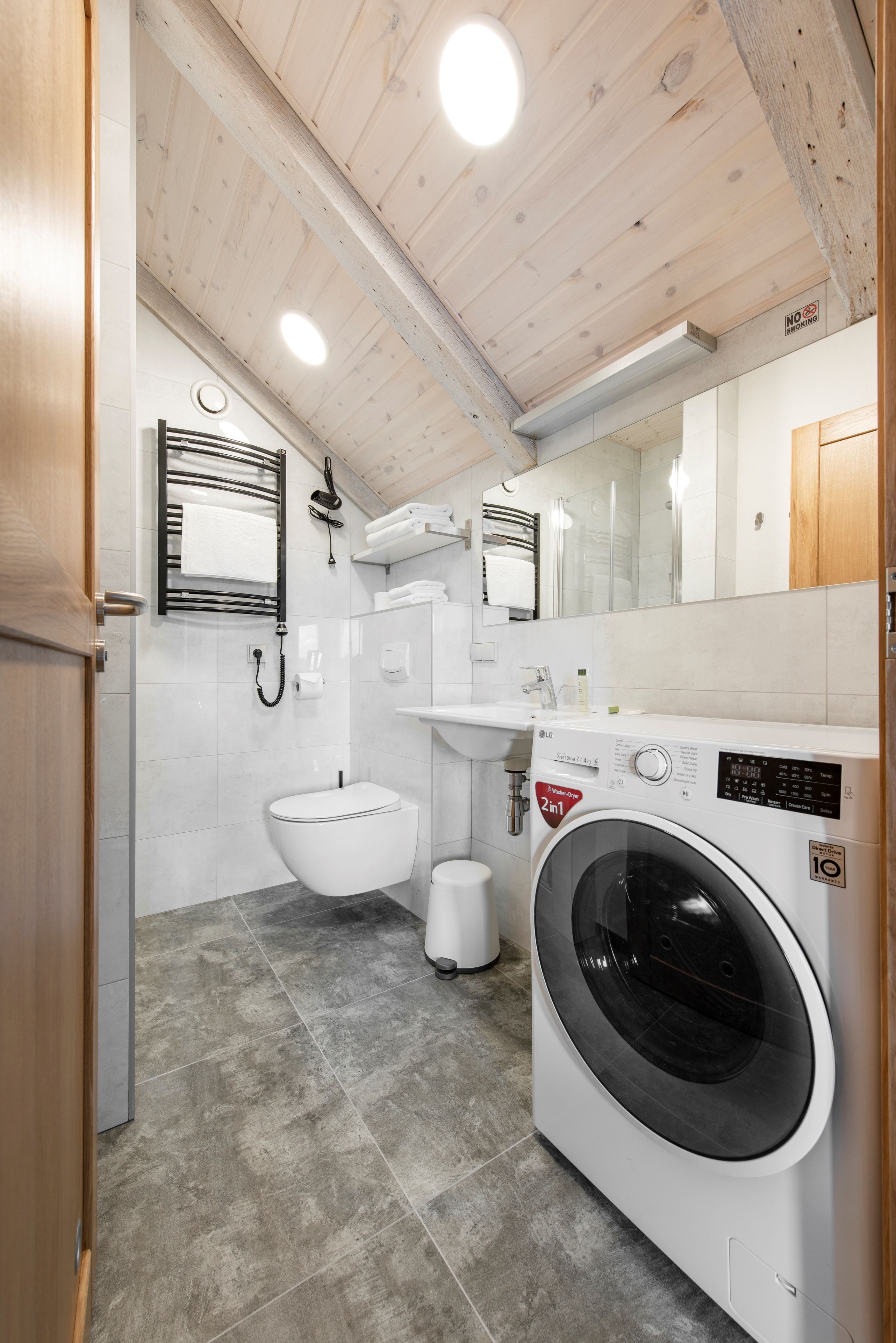 A compact bathroom with a washing machine, toilet, sink, and towel rack.