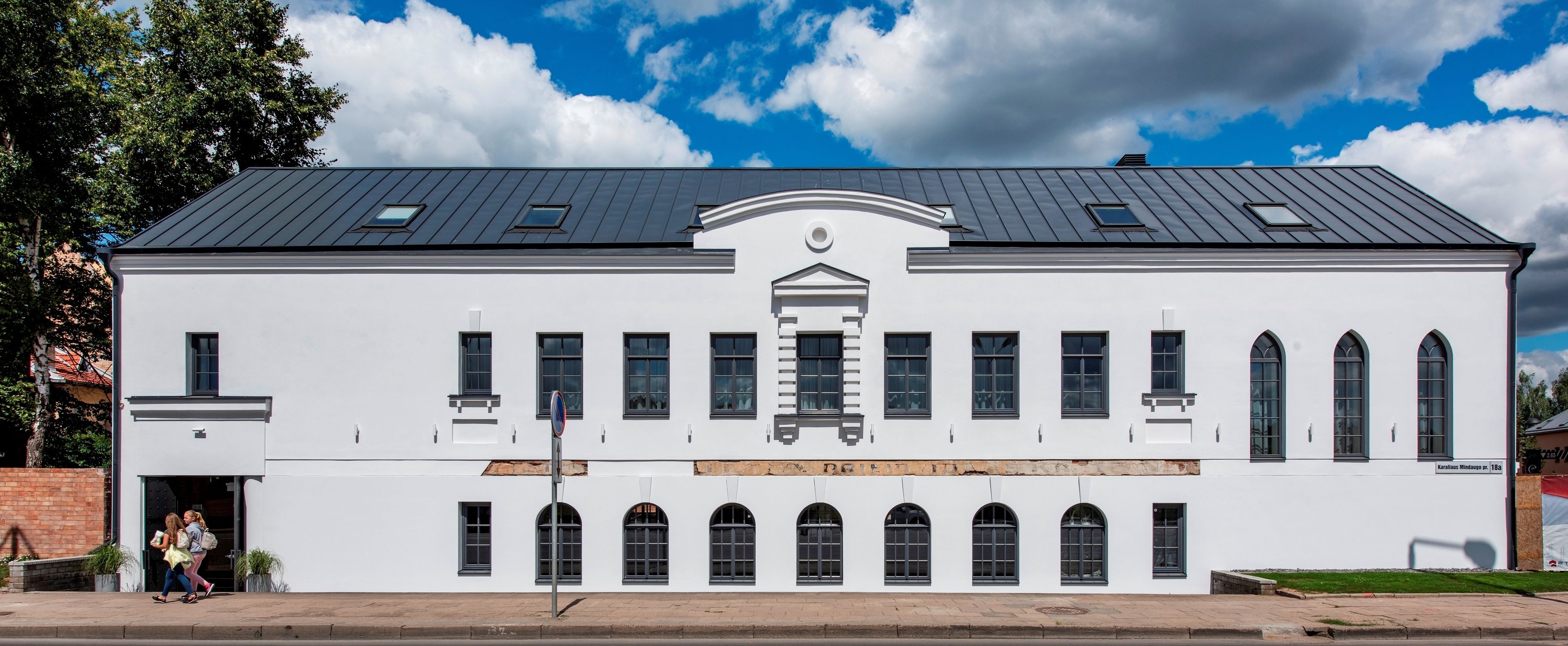 A white building with a dark roof, multiple windows, and a central entrance.