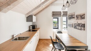 A modern kitchen with a wooden countertop, stainless steel sink, and hanging pendant lights.