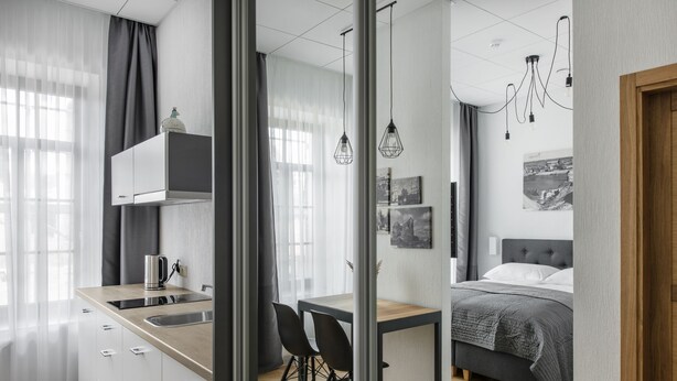 A modern bedroom with a bed, bedside table, and a view of the city.