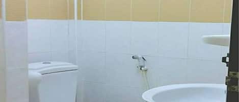 A small, compact bathroom with a toilet, sink, and shower.