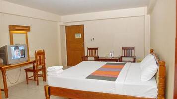 Una habitación de hotel con cama, televisión, escritorio y silla.