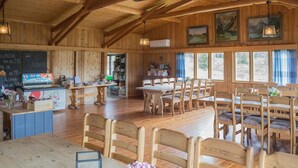 A wooden interior with a dining area, tables, chairs, a bar, and a chalkboard menu.