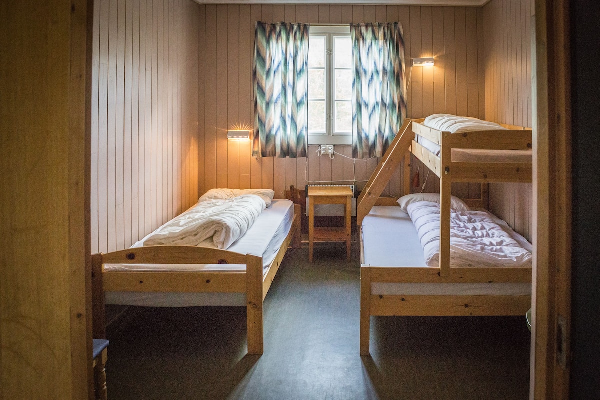 A room with two bunk beds, a small table, and a window with curtains.