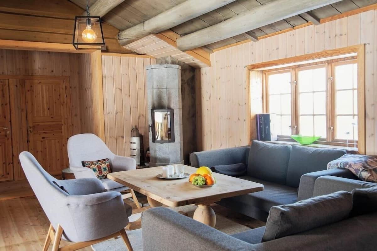 A cozy room with wooden walls, a stone fireplace, a sofa, and a table with fruit.