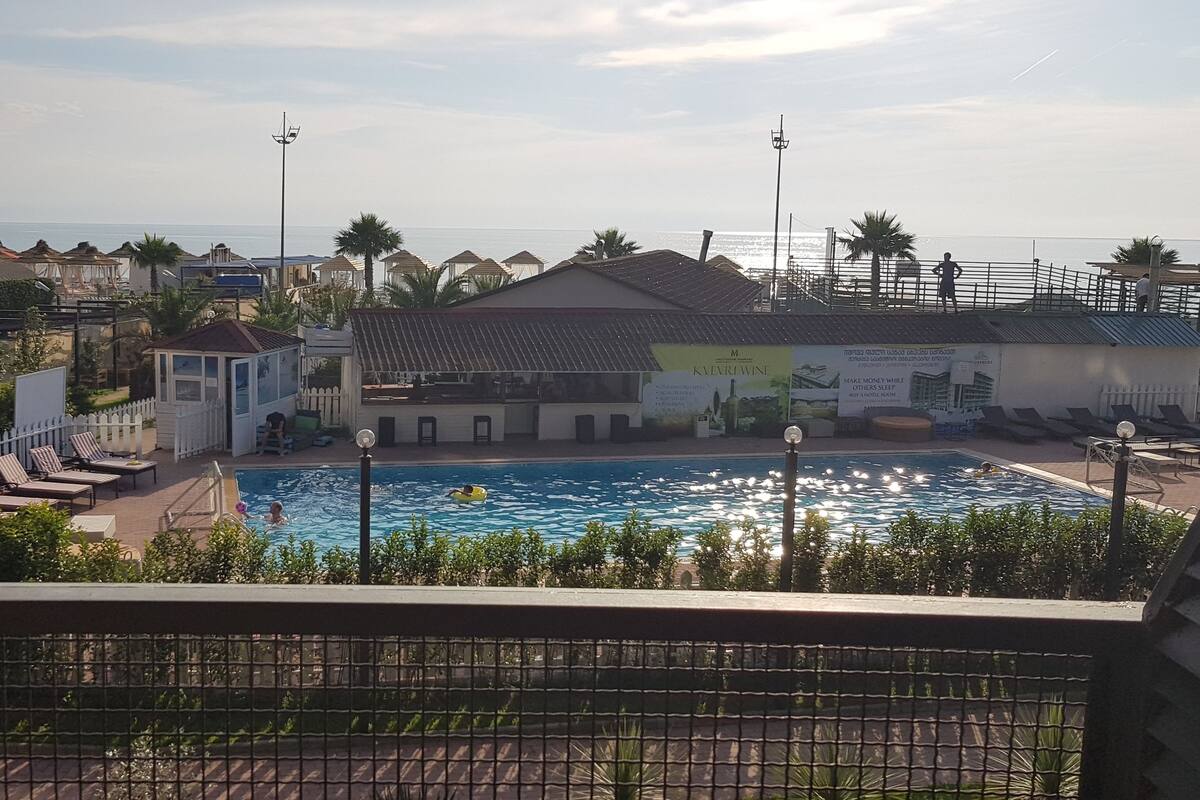 A pool area with lounge chairs and a building with a sign.