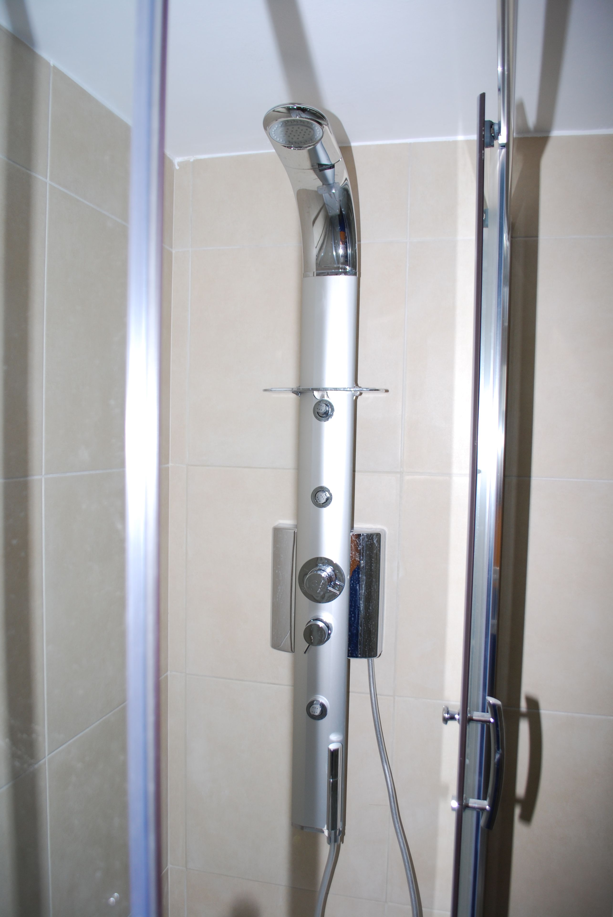 A shower with a chrome showerhead and control panel.