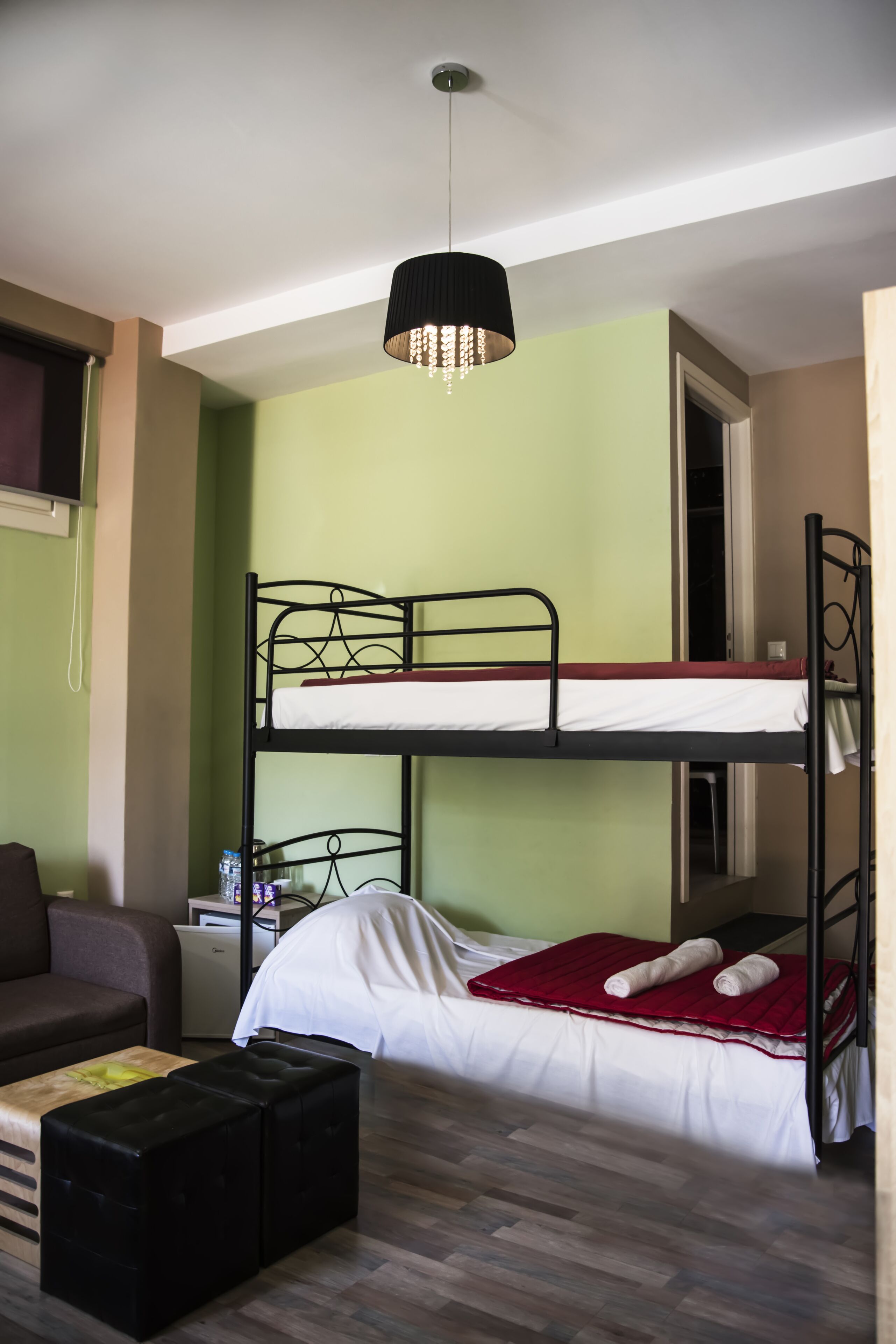 Quarto com beliche, escrivaninha, cadeira e luminária suspensa.