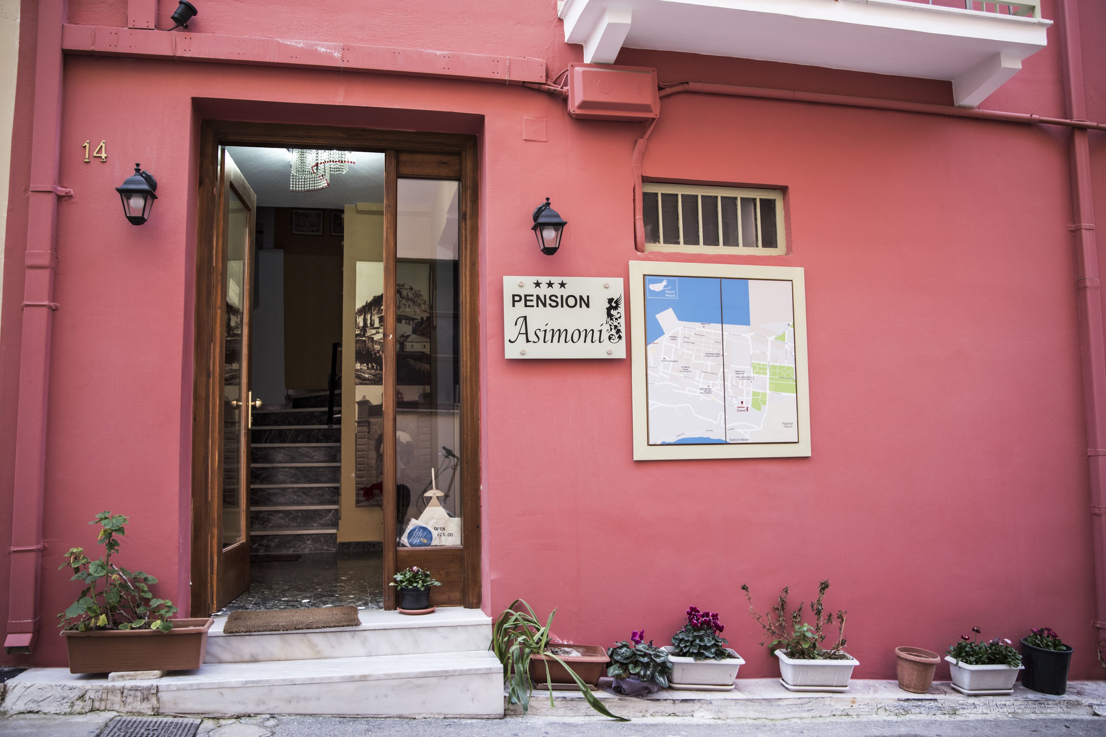 A building with a sign reading "Pension Asimoni" and a map on the wall.