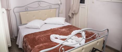 Una cama bien hecha con un cabecero color beige, almohadas blancas y una manta marrón. Hay una bata de baño blanca sobre la cama.