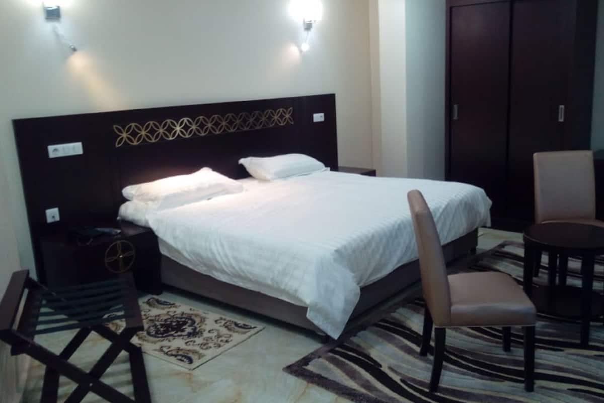 Een hotelkamer met een bed, een stoel, een klein tafeltje en een kledingkast.