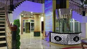 A modern hotel lobby with a marble floor, a reception desk, and a staircase. - Al Mansour Palace (Mazagran)