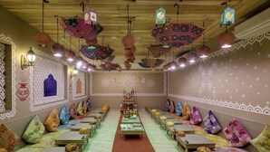 A traditional room with patterned walls, hanging lanterns, and neatly arranged cushions. - Radhey Ki Haveli (Danta Ramgarh)
