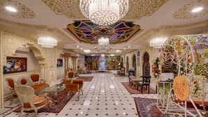 A luxurious hotel lobby with ornate chandeliers, a central floral arrangement, and traditional seating. - Radhey Ki Haveli (Danta Ramgarh)