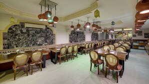 A restaurant with a long counter, multiple tables, and chairs. - Radhey Ki Haveli (Danta Ramgarh)