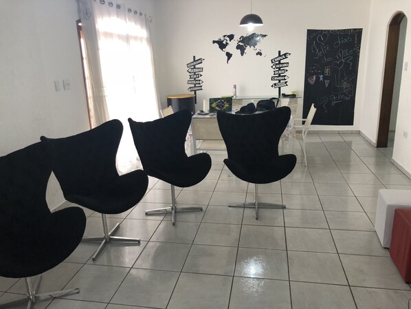 A waiting area with modern black chairs, a world map wall, and a chalkboard with travel-related drawings.