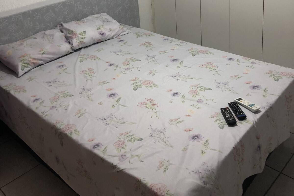 A bedroom with a bed, a nightstand, a wardrobe, and a painting on the wall.