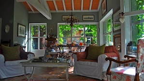 A cozy living room with a wooden ceiling, large windows, and a chandelier.