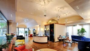 A spacious lobby with a reception desk, seating area, and a large decorative floor feature. - Hotel Miramare et de la Ville (Miramare di Rimini)