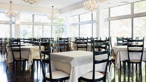 A spacious dining area with multiple tables and chairs, large windows, and chandeliers. - Hotel Miramare et de la Ville (Miramare di Rimini)