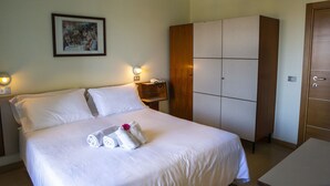A hotel room with a bed, a wardrobe, a nightstand, a framed picture on the wall, and a small table with a telephone. - Hotel Miramare et de la Ville (Miramare di Rimini)