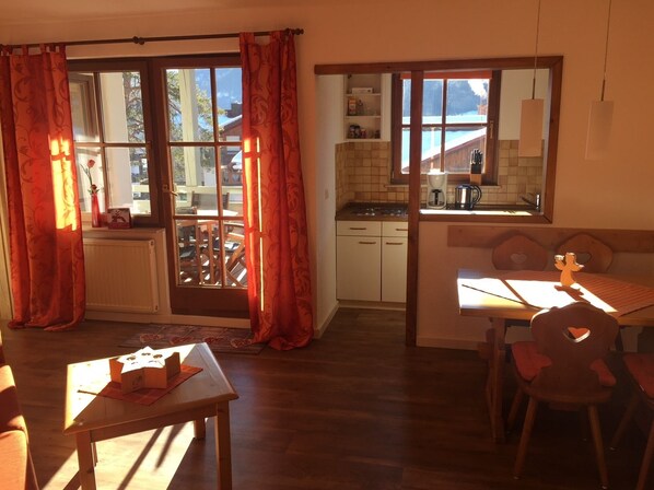 A cozy kitchen with a view, wooden cabinets, and a dining area with a table and chairs.